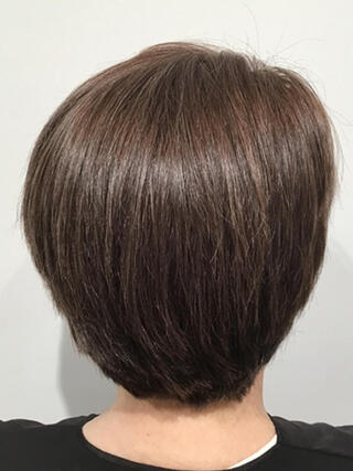 Foto de después: vista trasera de una mujer con cabello corto y castaño sin canas después de la coloración.