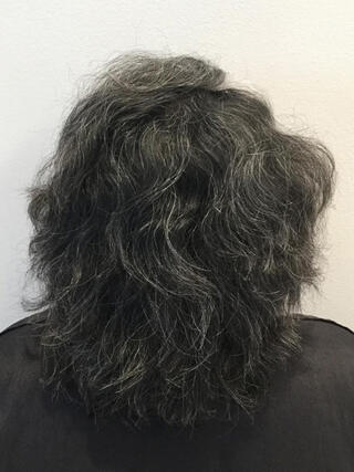Foto de antes: vista trasera de una mujer con cabello negro corto con muchas canas antes de la coloración.